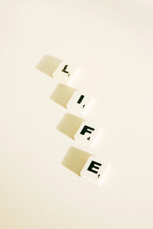 the word life spelled in scrabbles on a white surface, an album cover, unsplash, life cycle, afterlife, in a row, late night