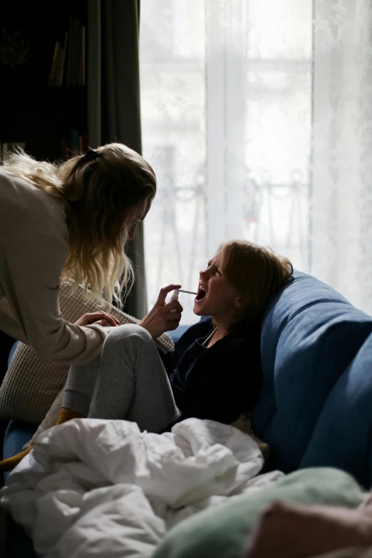 a couple of women sitting on top of a couch, pexels contest winner, movie still of a snarling, sick with a cold, young girls, julia hetta