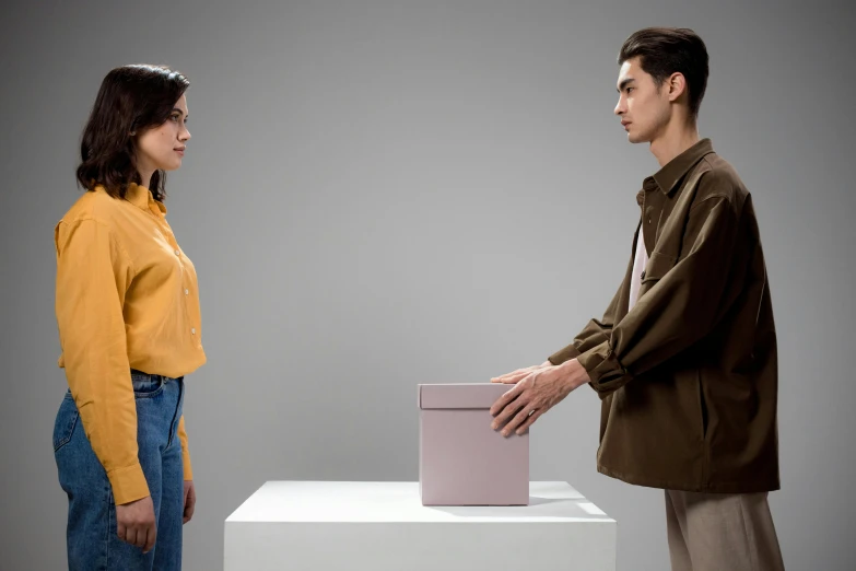 a man and a woman standing in front of a box, trending on pexels, conceptual art, calmly conversing 8k, plain background, ignant, holding gift