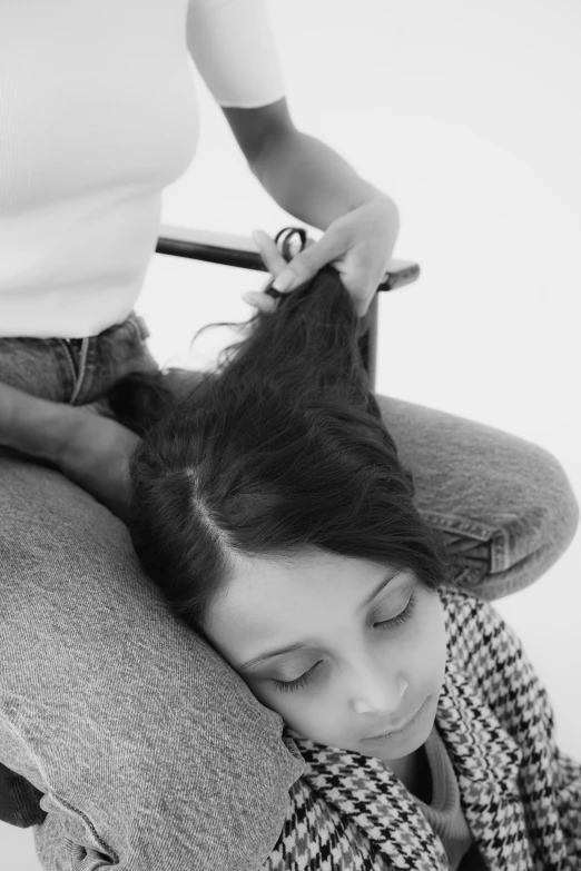 a woman sitting in a chair combing another woman's hair, a black and white photo, by Clifford Ross, lying on back, 2 0 0 6, close - up photograph, max dennison