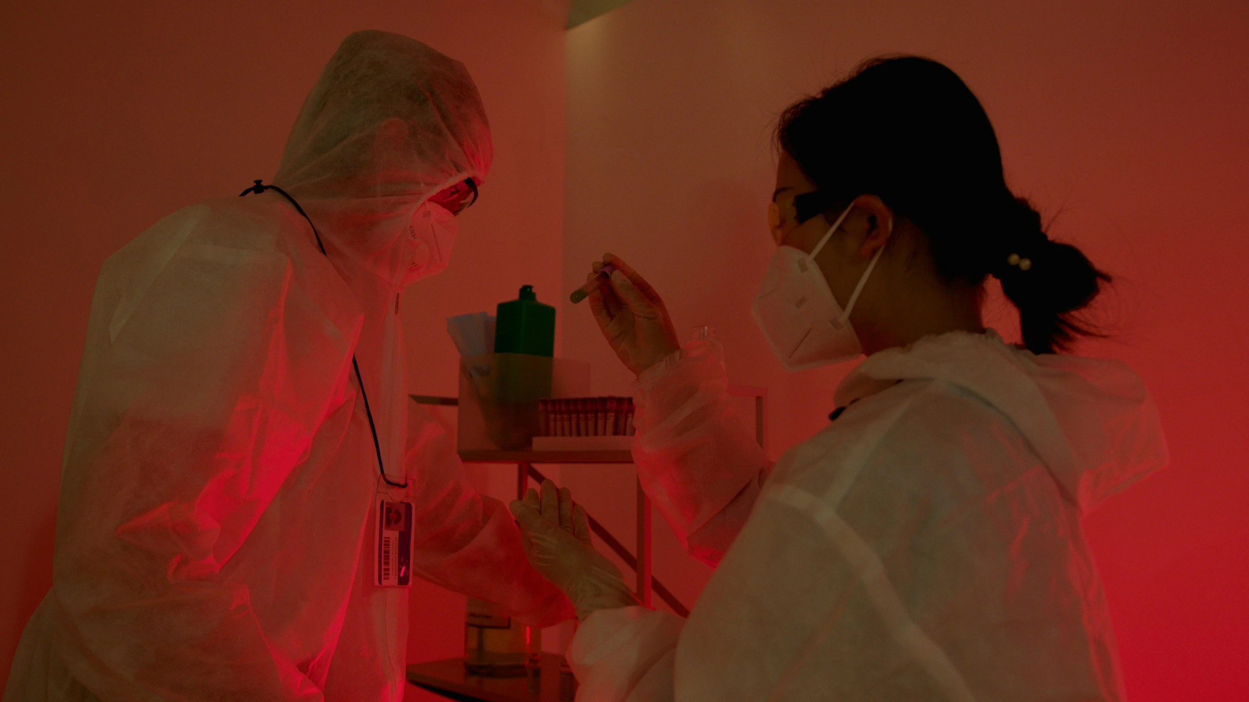 a couple of people that are in a room, holding a syringe, red laser, staff wearing hazmat suits, profile image