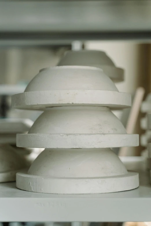 a close up of a stack of plates on a shelf, an abstract sculpture, inspired by Rachel Whiteread, unsplash, concrete art, domes, introduction factory photo, ready to model, made of cement and concrete