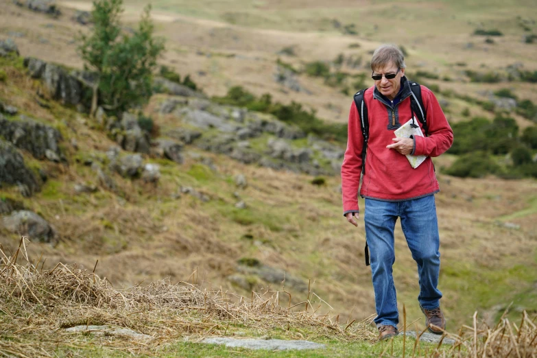 a man standing on top of a grass covered hillside, by Kev Walker, pexels, plein air, structural geology, walking towards camera, avatar image