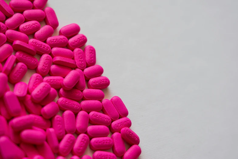 a pile of pink pills on a white surface, pexels, antipodeans, ((pink)), fluorescent colours, cover shot, adafruit