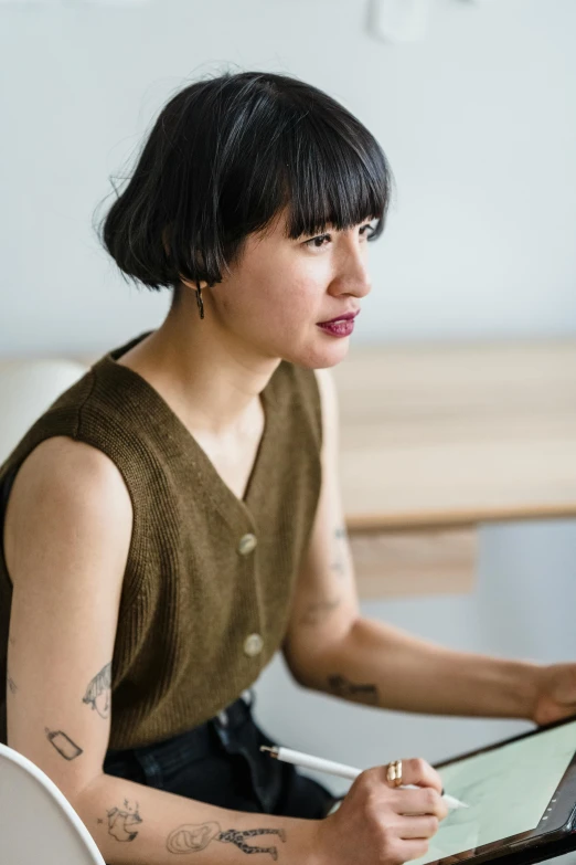 a woman sitting in front of a laptop computer, a portrait, by Winona Nelson, with a bob cut, bao pham, wooden jewerly, looking serious