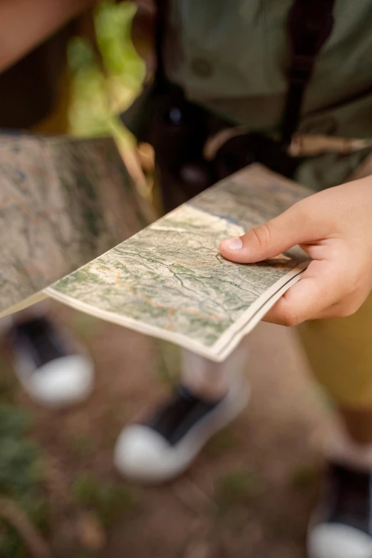 a close up of a person holding a map, campsites, center of interest, camo, multiple stories