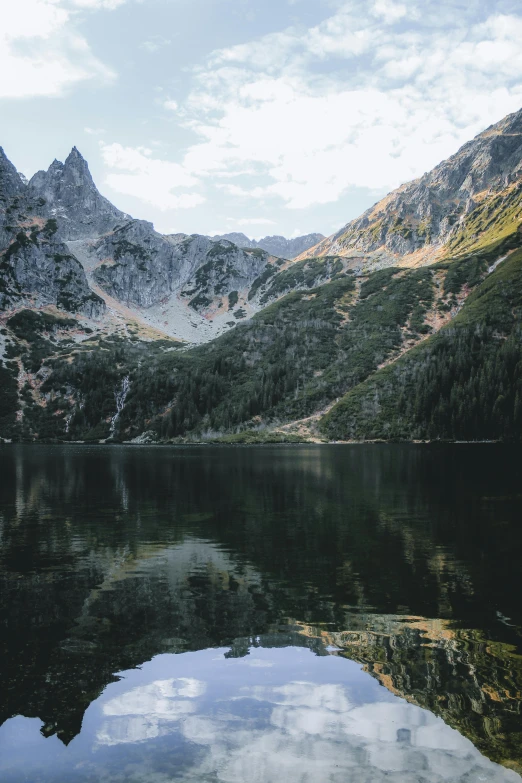 a body of water with mountains in the background, by Adam Marczyński, poland, tall spires, high-quality photo, multiple stories