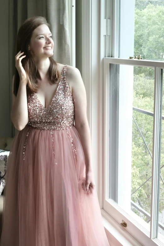 a woman standing in front of a window talking on a cell phone, a picture, by Hannah Tompkins, reddit, pink glitter mermaid gown, 2 5 6 x 2 5 6 pixels, rose gold, wearing a pink tutu