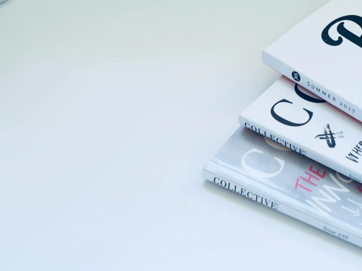 a stack of three books sitting on top of a table, unsplash contest winner, private press, white minimalist architecture, detailed letters, fashion magazines, taken in the late 2010s