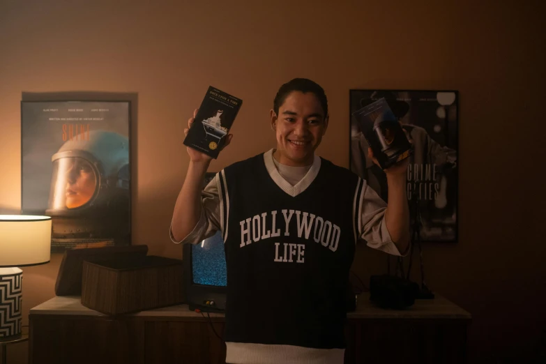 a man standing in a living room holding a book, inspired by Eddie Mendoza, at netflix, gamer, hollywood movie still, high school