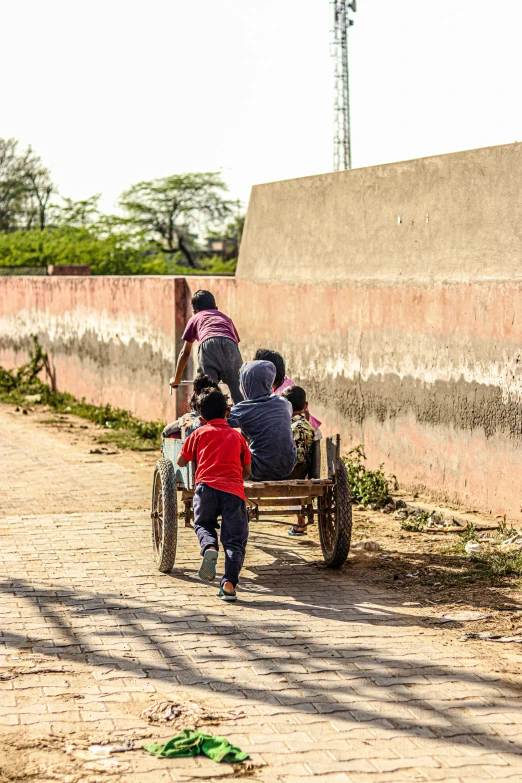 a group of people riding on the back of a horse drawn carriage, by Jan Tengnagel, pexels contest winner, conceptual art, behind a tiny village, kids playing, cairo, spring season