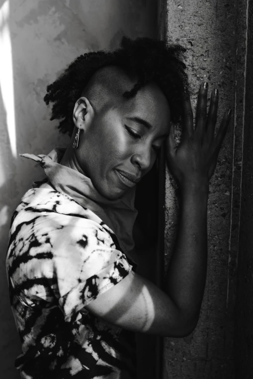 a black and white photo of a man leaning against a wall, a black and white photo, inspired by Carrie Mae Weems, short dreadlocks with beads, ashteroth, lucio as a woman, uploaded