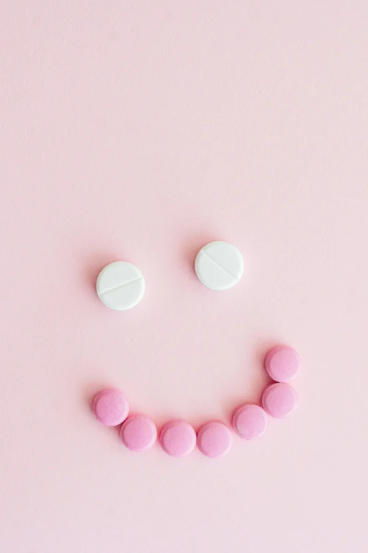 a smiley face made out of pills on a pink background, a picture, trending on pexels, antipodeans, 15081959 21121991 01012000 4k, sweets, ✨🕌🌙, minimalissimo