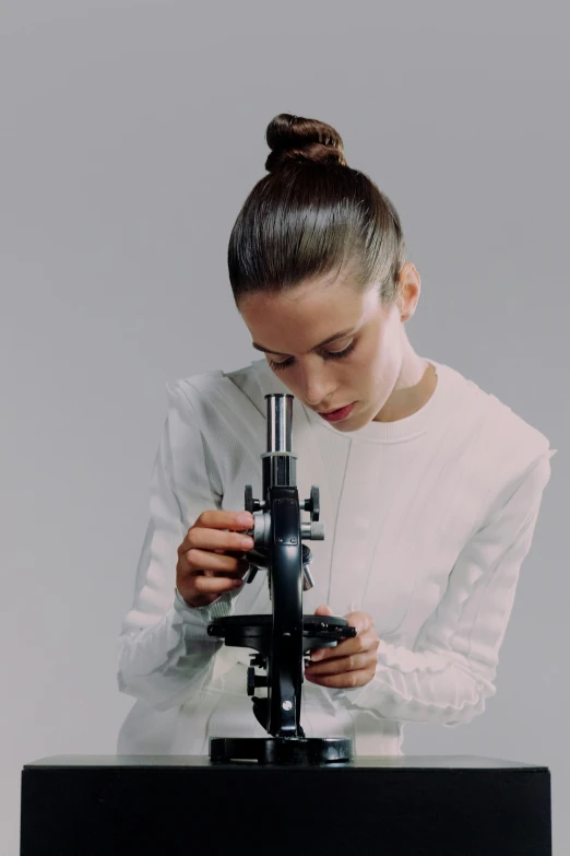 a woman in a white shirt looking through a microscope, inspired by Anna Füssli, portrait sophie mudd, wearing nanotech honeycomb robe, subtle detailing, college