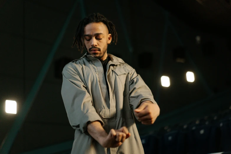 a man standing on top of a tennis court holding a racquet, an album cover, inspired by Afewerk Tekle, pexels contest winner, antipodeans, chappie in an adidas track suit, performing on stage, trench coat with many pockets, thumbnail
