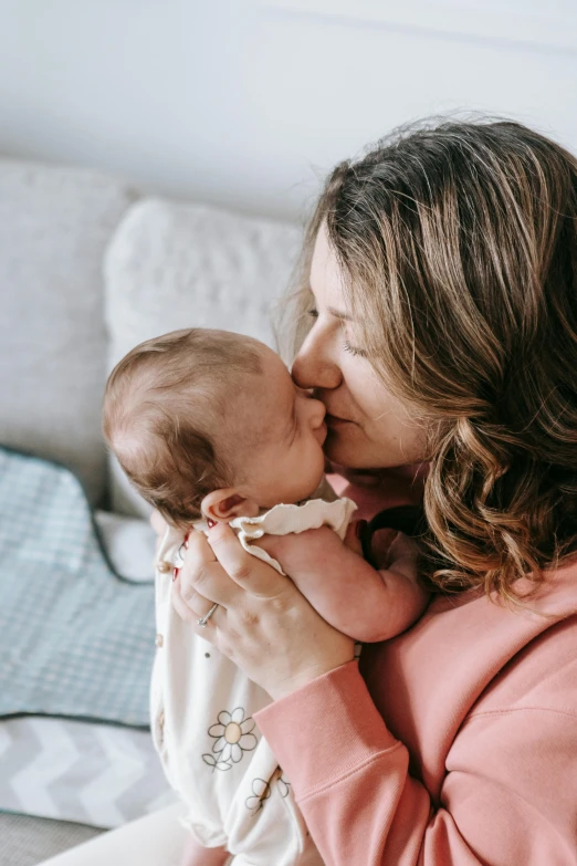 a woman sitting on a couch holding a baby, pexels contest winner, happening, kissing each other, close up portrait, bedhead, profile image