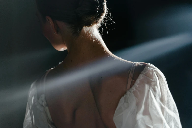 the back of a woman in a white dress, unsplash contest winner, light and space, fashion week backstage, beams of light, photography ultrafine detail, moody evening light