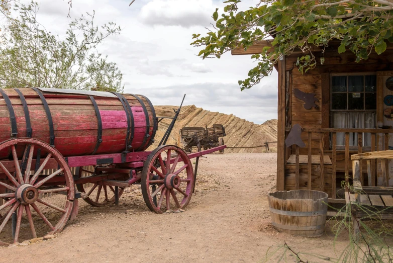 a wagon that is sitting in the dirt, by Linda Sutton, pexels contest winner, renaissance, brown and pink color scheme, entrance to 1900's mine, near his barrel home, las vegas