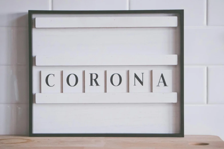 a sign sitting on top of a wooden table, inspired by Edward Ruscha, trending on unsplash, international typographic style, poster of corona virus, square pictureframes, the chronic, with a white background
