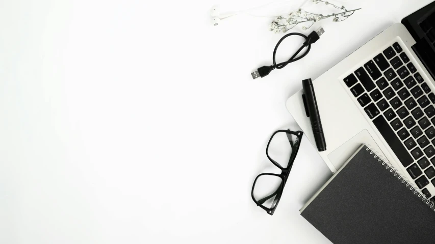 a laptop computer sitting on top of a white desk, black rimmed glasses, hair are curled wired cables, white paper background, background image