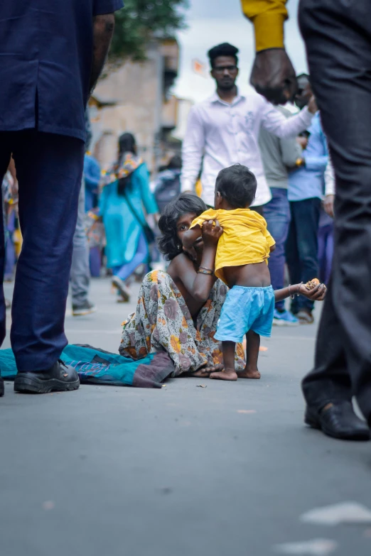 a group of people that are sitting on the ground, by Matt Stewart, pexels contest winner, hurufiyya, colombo sri lankan city street, woman holding another woman, with a kid, hunger