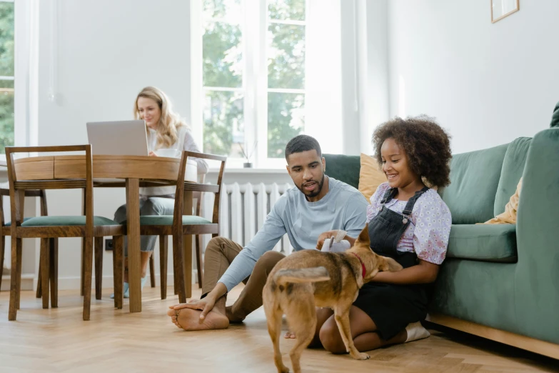 a man and woman sitting on the floor with a dog, on a table