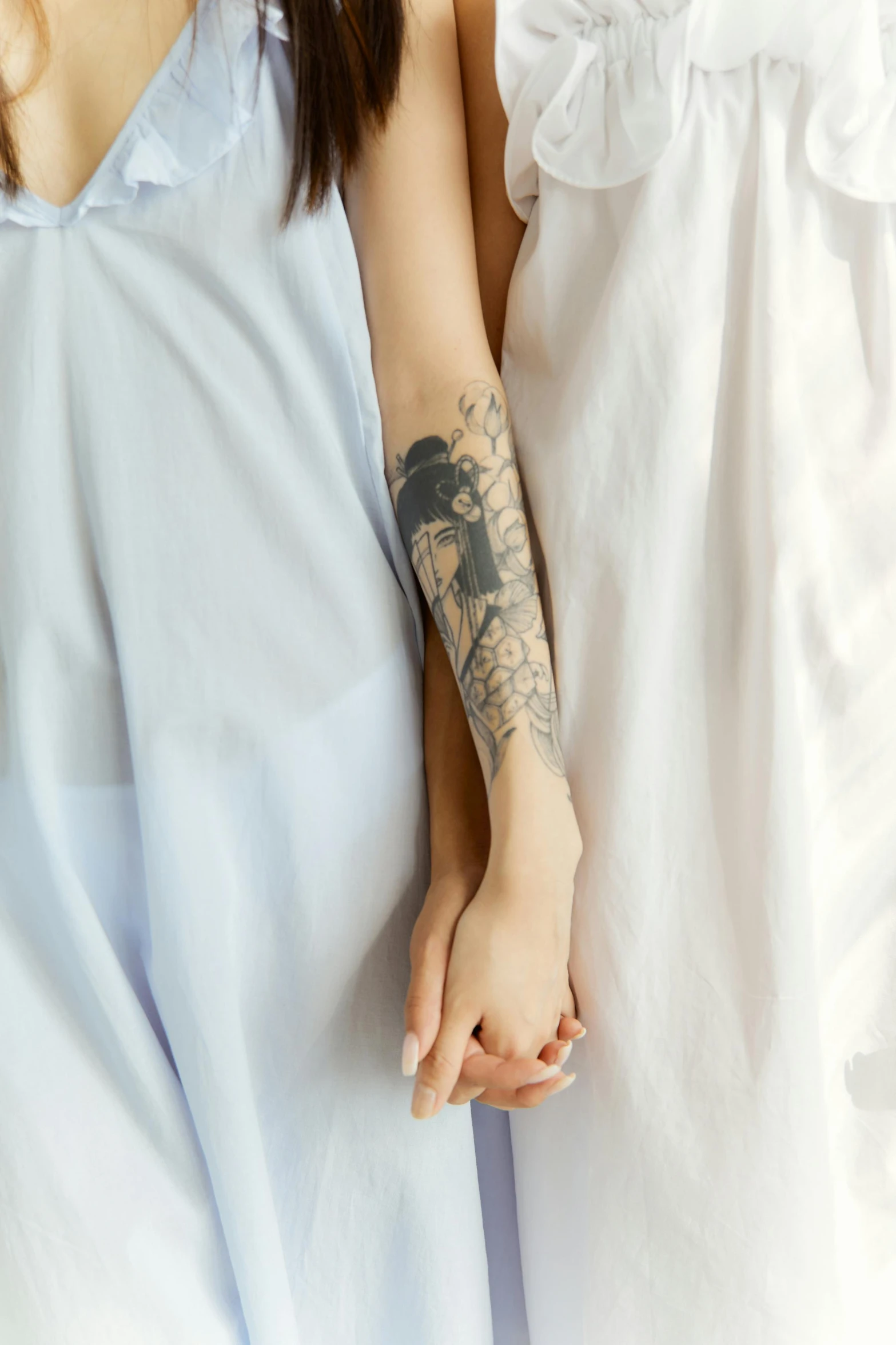 a couple of women standing next to each other on a bed, a tattoo, inspired by Elsa Bleda, trending on pexels, romanticism, photograph of a sleeve tattoo, soft shadow transition, on a gray background, porcelain skin ”