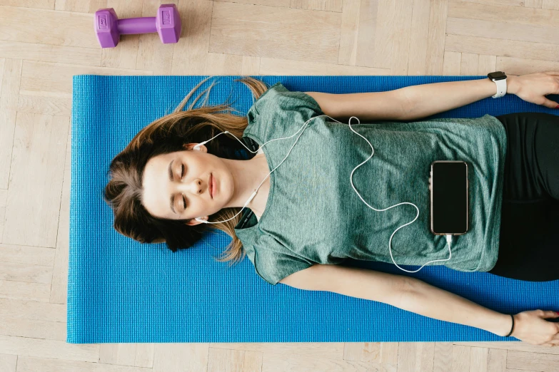 a woman laying on a yoga mat with headphones on, trending on pexels, avatar image, taken on iphone 14 pro, full - body artwork, background image