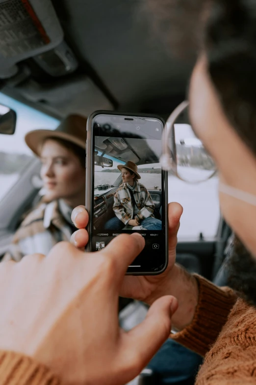 a man taking a picture of a woman in a car, trending on pexels, phone wearing a cowboy hat, avatar image, moody neutral hipster tones, iphone video