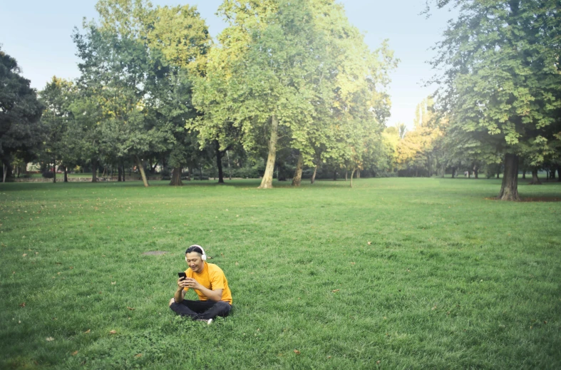 a man sitting on top of a lush green field, berlin park, camera photo, ismail, [ realistic photography ]