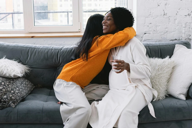 a couple of women sitting on top of a couch, pexels contest winner, happening, sweet hugs, connection rituals, essence, diverse