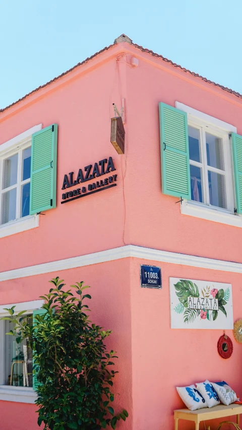 a pink building with green shutters on a sunny day, alizarin curtains, official store photo, sign, zaba style