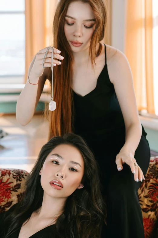 a woman combing another woman's hair in a living room, a portrait, inspired by Wang Duo, trending on pexels, brown red long hair, asian human, promotional image, looking towards camera