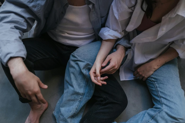 a couple of women sitting next to each other, trending on pexels, pile of bodies, hands hidden, boys and girls, woman holding another woman