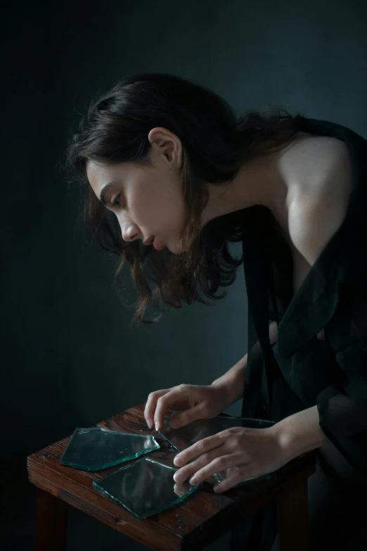a woman sitting at a table using a tablet computer, inspired by Anna Füssli, pexels contest winner, figurative art, broken mirror, dark. studio lighting, pale skin, resin