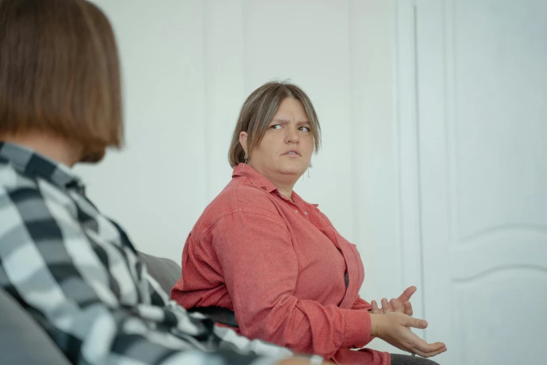 a woman sitting on top of a couch next to a man, a cartoon, unsplash, hyperrealism, in a meeting room, a portrait of a plump woman, low quality photo, realistic »