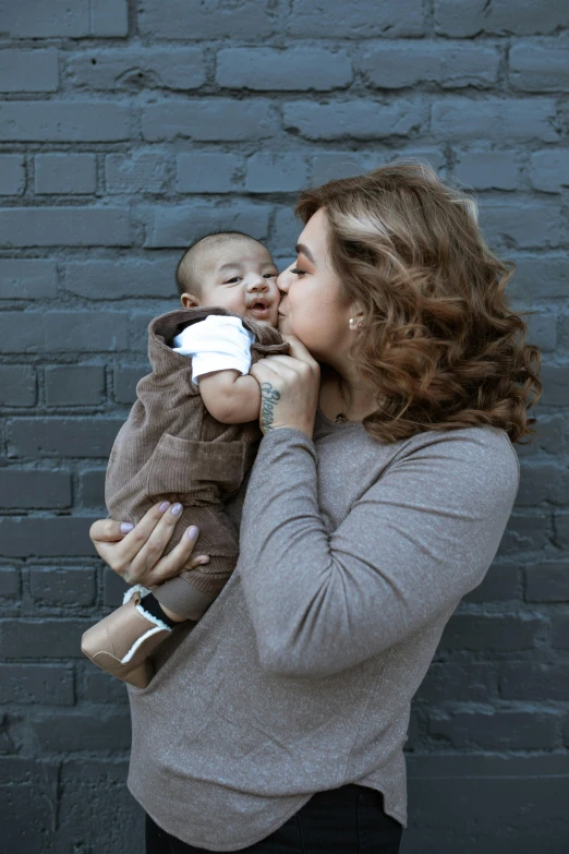 a woman holding a baby in her arms, a photo, by Carey Morris, pexels contest winner, non binary model, hispanic, kiss, square