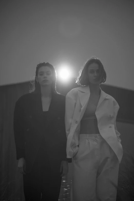 a couple of women standing next to each other, a black and white photo, inspired by Wang Duo, unsplash, lit in a dawn light, jiyun chae, bowater charlie and brom gerald, music video
