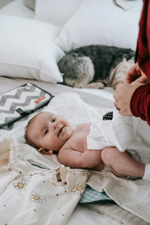 a woman holding a baby on top of a bed, pexels contest winner, happening, diaper disposal robot, flatlay, cute boys, wrinkles