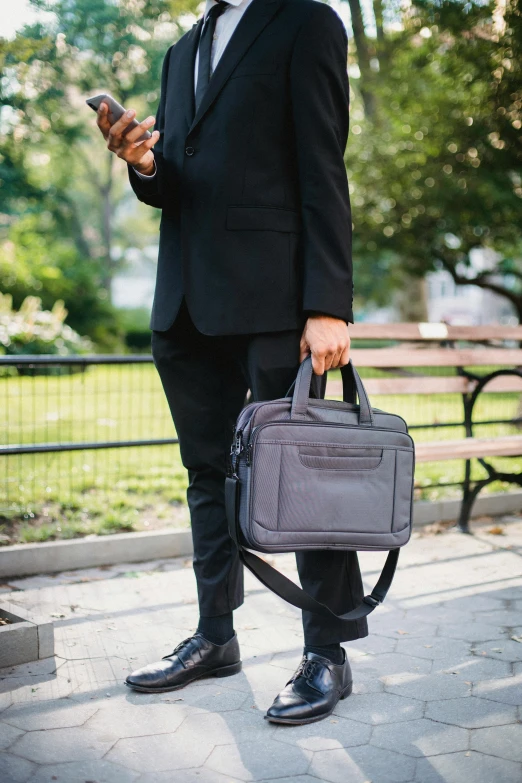 a man in a suit and tie holding a briefcase, in a city park, 💣 💥💣 💥, smooth technology, gray canvas