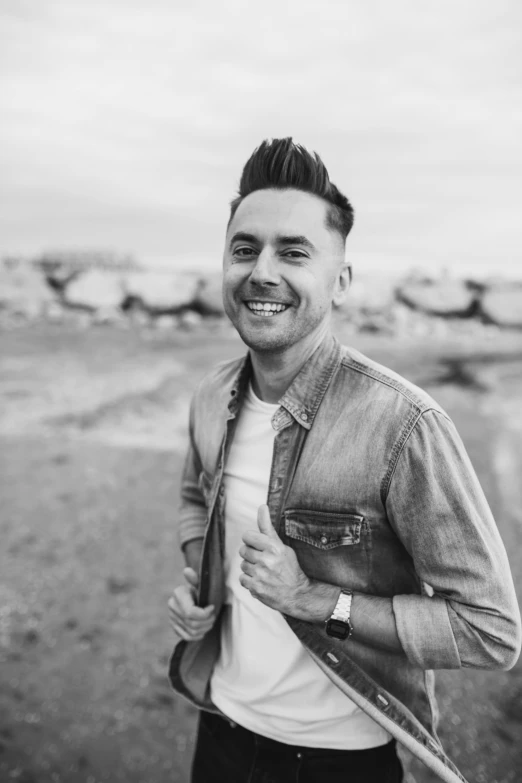 a black and white photo of a man smiling, inspired by Michael James Smith, irish youtuber, standing in the desert, pompadour, bright lights