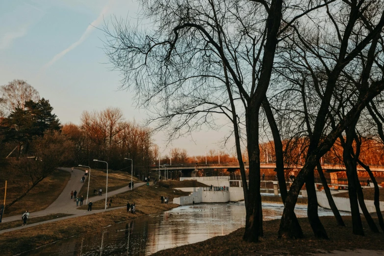 a body of water surrounded by trees and a bridge, by Niko Henrichon, pexels contest winner, visual art, in legnica, people watching around, late afternoon light, 2 0 0 0's photo