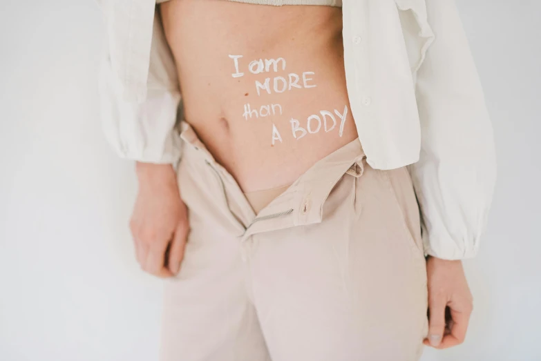 a woman with the words i don't more than a body written on her stomach, by Emma Andijewska, trending on pexels, full - body artwork, healthcare, male body, white body