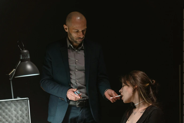 a man standing next to a woman in front of a laptop, by Adam Marczyński, pexels contest winner, hyperrealism, lighting her with a rim light, photoshoot for skincare brand, gustave dore and marco mazzoni, in a black room