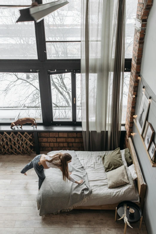 a woman laying on top of a bed in a bedroom, inspired by Elsa Bleda, pexels contest winner, picture of an interior loft, standing near a window, bird view, winter snow