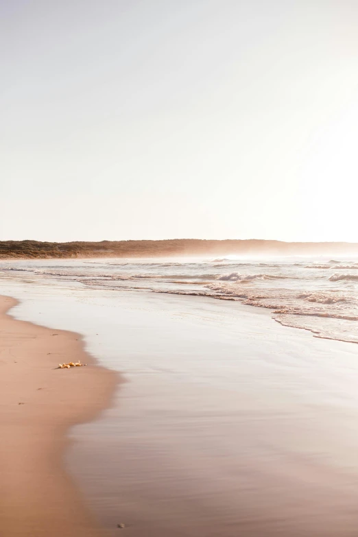 a man riding a surfboard on top of a sandy beach, by Peter Churcher, unsplash, minimalism, pink landscape, soft morning light, minn, wide long view