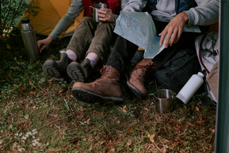 a group of people sitting on the ground next to a tent, trending on pexels, leather boots, moss growing on their clothes, profile image, cast