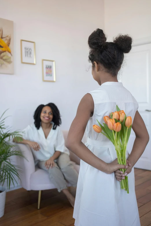 a woman in a white dress holding a bunch of flowers, by Dan Content, pexels contest winner, with a kid, location in a apartment, african american young woman, promo still