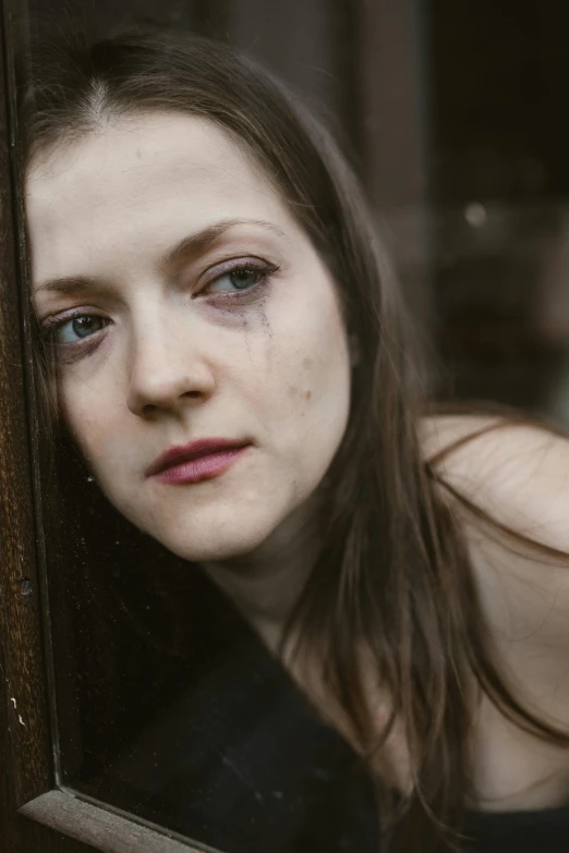 a close up of a person looking out a window, inspired by Elsa Bleda, renaissance, tears running down face, photo of young woman, with a hurt expression, pale round face