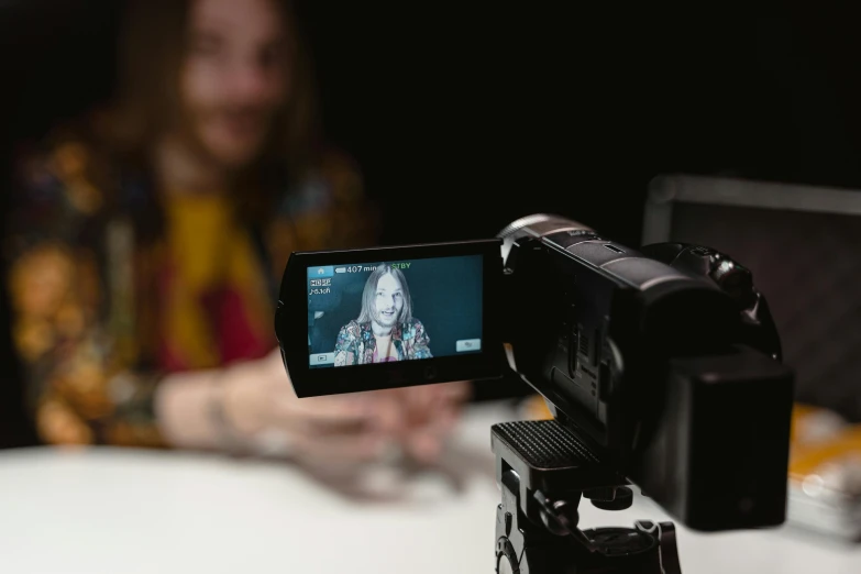 a video camera sitting on top of a tripod, a picture, unsplash, video art, person in foreground, sitting in front of a microphone, avatar image, colour photograph